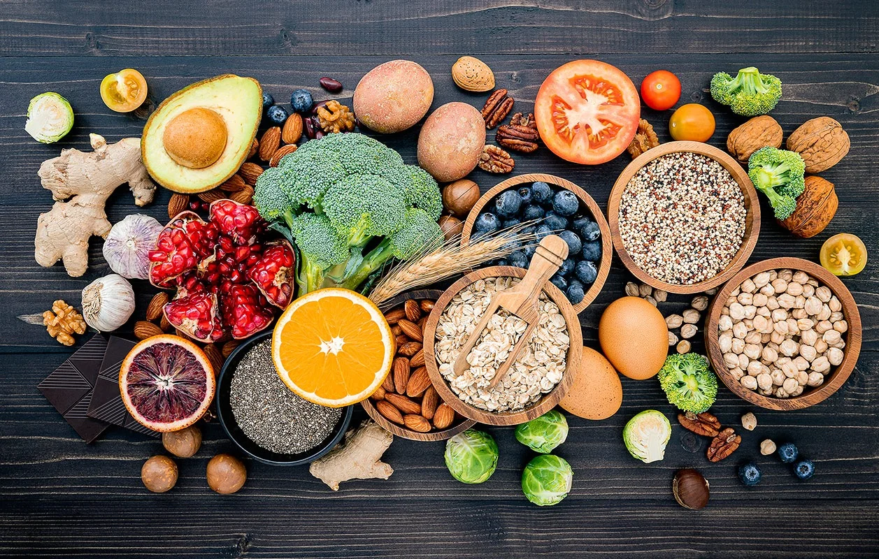 Healthy Foods for Weight Loss and Wellness Healthy natural foods including fruits, vegetables, nuts, and grains on a dark wooden table.