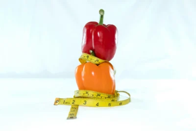 Fresh bell peppers wrapped with a measuring tape, representing healthy nutrition and CLA-rich foods.