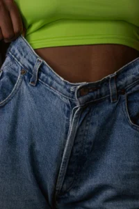 Slim waist with loose jeans, showing progress after CLA-supported weight loss.