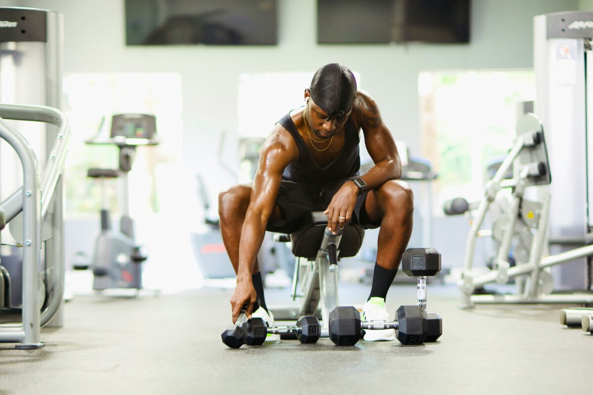 Muscular man lifting dumbbells in a modern gym